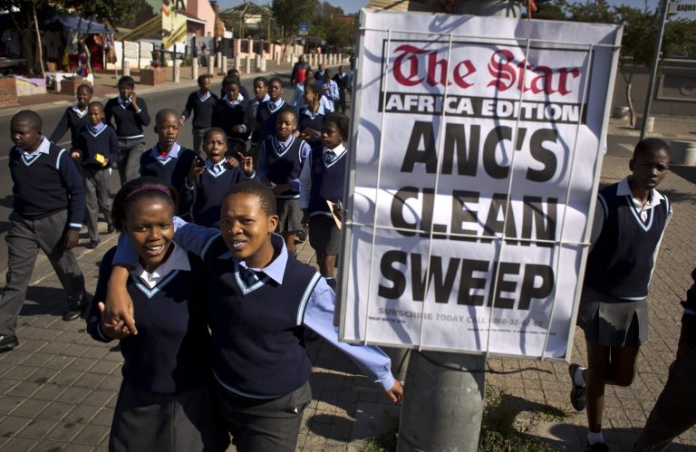 Schoolchildren walk past a newspaper placard reporting the election victory of Jacob Zuma's African National Congress (ANC) party, based on preliminary results, as the children leave after making a visit to the former house of the late South African President Nelson Mandela, in the Soweto township of Johannesburg, South Africa Friday, May 9, 2014. Vote-counting in elections in South Africa is almost complete, indicating a comfortable win for the ruling African National Congress but also a strengthening of key opposition rivals that promised change after 20 years of leadership by the party that led the fight against apartheid. (AP Photo/Ben Curtis)