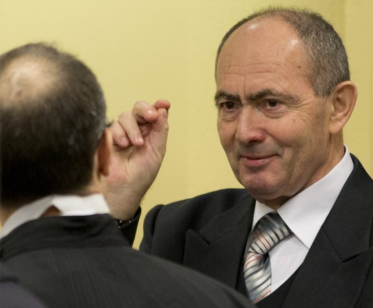   Zdravko Tolimir, right, a former high-ranking Bosnian Serb army officer charged with crimes including genocide in the 1995 Srebrenica massacre, crosses himself as he waits for the the Yugoslav war crimes tribunal to deliver its judgment in The Hague, Wednesday Dec. 12, 2012. (AP Photo/Peter Dejong, Pool)  