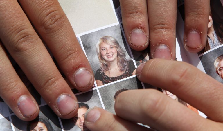 FILE - In this May 29, 2014 file photo, Wasatch High School sophomore Rachel Russell, 16, points to her altered school yearbook photo, center, in Heber City, Utah. Russell is one of several students at the school whose yearbook photos were digitally altered, with sleeves and higher necklines drawn on to cover up bare skin. Russell said Tuesday, June, 3, that she has since received a phone call from the school's principal, who explained he was sorry for the ordeal. (AP Photo/Rick Bowmer, File)