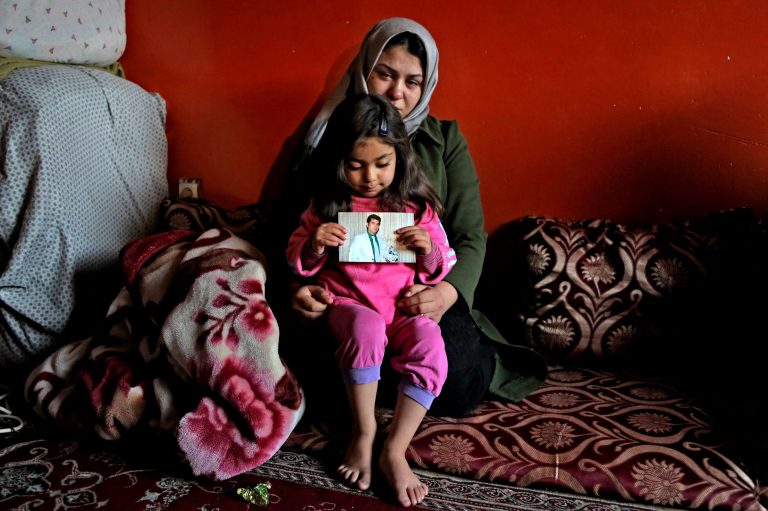 In this Wednesday, Feb 12, 2014 photo, Afghan widow, Zar Afshan, 21, holds her daughter as she shows her father's picture, at her parents' home in Kabul, Afghanistan. Afshan's in-laws forced her to return to her parents' home after her husband was killed during an attack on the Taverna du Liban restaurant few weeks ago in Afghan capital Kabul.  Afghan President Hamid Karzai has ordered changes to a draft of new criminal legislation in response to an international outcry warning it would severely limit justice for victims of domestic abuse, his spokesman said Monday. (AP Photo/Rahmat Gul)