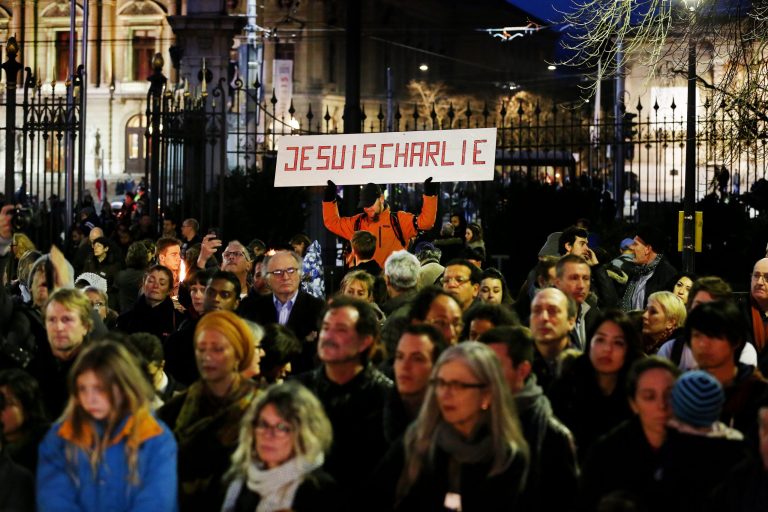 In this Saturday Jan. 10, 2015 picture, people hold torches and posters reading 