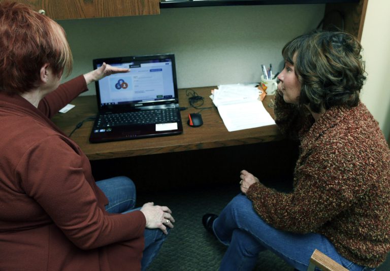 In this photo on Wednesday, Dec. 18,  Caring Hearts Clinic director Sue Cook, left, helps Kathy Bannister with enrolling in the Affordable Care Act at the free clinic in Marlette, Mich. (AP Photo/Carlos Osorio)