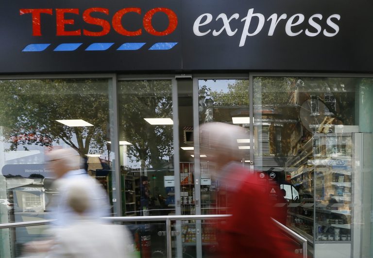 Pedestrians pass a Tesco shop in London, Monday, Sept. 22, 2014. Tesco, Britain's largest retailer by revenue, has suspended four executives and launched an accounting investigation after admitting that its half-year profit was overstated by 250 million pounds ($407 million). (AP Photo/Kirsty Wigglesworth)