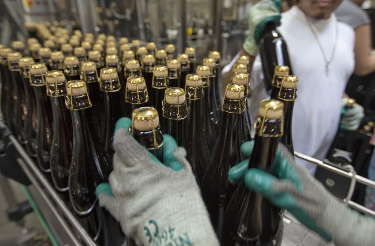   FILE - In this July 1, 2013 file photo, bottles of Brooklyn Local 2, a Belgian-inspired Dark Abbey Ale, are loaded on to a conveyor for labeling, at the Brooklyn Brewery, in the Williamsburg section of the Brooklyn borough of New York. The Federal Reserve reports on output from U.S. factories, mines and utilities in July on Thursday, Aug. 15, 2013. (AP Photo/Richard Drew, File)  