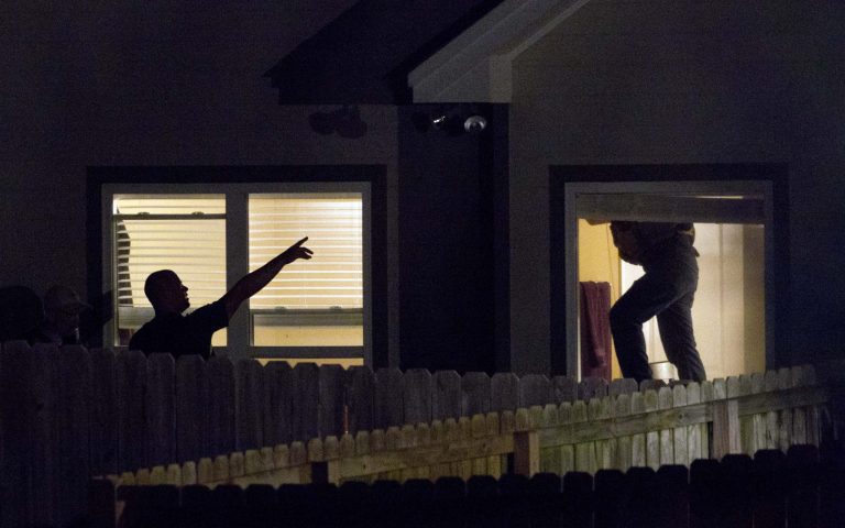   Law enforcement officials search a home in Montgomery, Ala., Monday, June 11, 2012. Authorities searching for the man charged with fatally shooting three people near Auburn University swarmed the house Monday where they believe he's hiding, firing tear gas and sending a tactical team on cautious forays inside. (AP Photo/Dave Martin)  