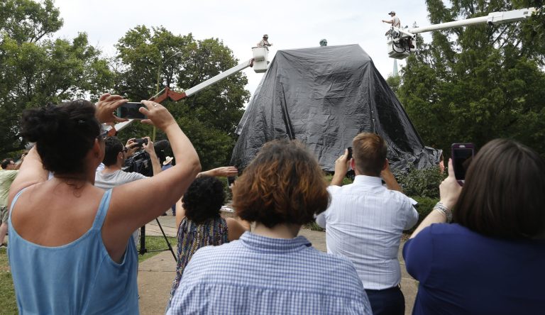 An armed man wearing a tie dye shirt attempted cut down a tarp that was placed over the Robert E. Lee statue in Charlottesville, Va. on Wednesday. (AP Photo/Steve Helber)