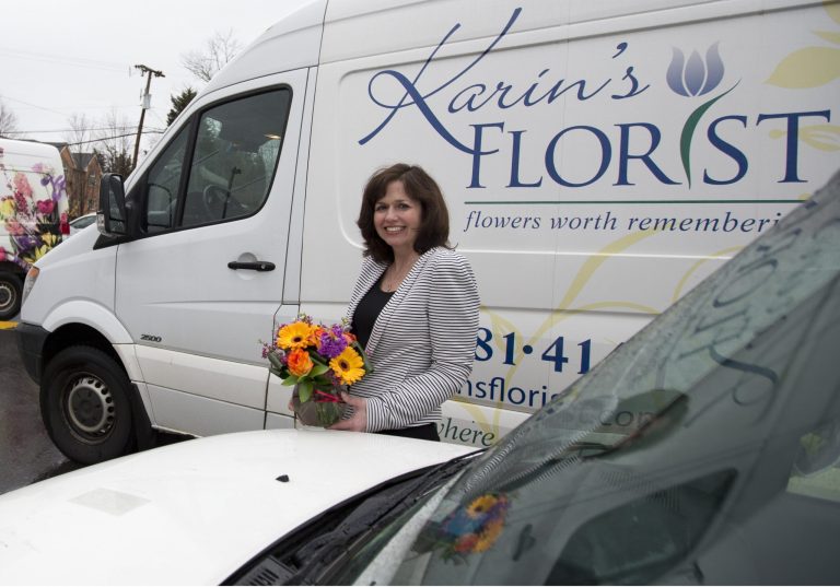 In this Friday, Feb. 21, 2014, photo, Maris Angolia, president of Karin's Florist, stands with two of Karin's Florist's delivery vehicles, a 2006 Scion xB, front, and a 2011 Mercedes-Benz Sprinter, behind, outside Karin's Florist, in Vienna, Va. (AP Photo/Carolyn Kaster)
