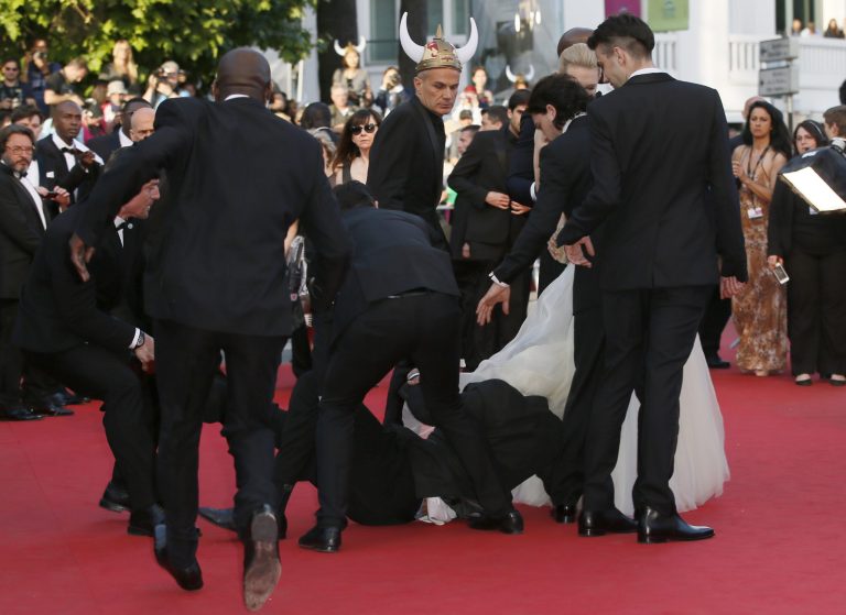 Actor Dijmon Hounsou, left, runs toward an unidentified man who ran unauthorized onto the red carpet during arrivals for the screening of How to Train Your Dragon 2 at the 67th international film festival, Cannes, southern France, Friday, May 16, 2014. (AP Photo/Alastair Grant)