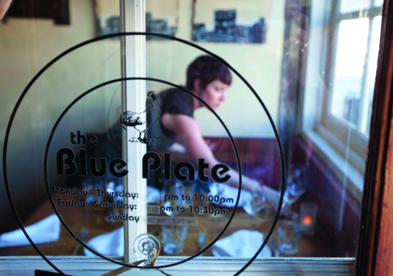 In this photo taken Wednesday, Aug. 29, 2012 a waitress sets a table for dinner at the Blue Plate restaurant in San Francisco. Nearly 200 San Francisco businesses charge diners and other customers an extra fee to pay for employee health care, but millions of dollars of it never gets spent on doctor visits or medicine. An Associated Press analysis of city records shows 59 percent of businesses that impose health care surcharges of about 3 per cent to 5 per cent on their clientele collected an average of $61,000 more than they spent on health care last year. Blue Plate suspended the fee because many of the young, healthy employees didn't have many medical expenses. (AP Photo/Eric Risberg)