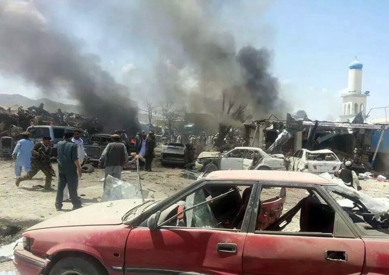 Afghanistan's security forces and civilians walk at the site of a suicide attack in the Urgun area of Paktika province, Afghanistan, Tuesday, July 15, 2014. The attack near a busy market and a mosque killed at least 89 people in the deadliest insurgent attack on civilians since the 2001 U.S.-led invasion. (AP Photo/Pajhwok News Agency)