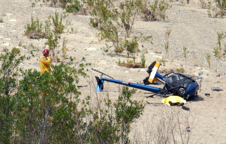 This image provided by the Santa Paula Times shows the crash site of a Robinson R22 helicopter in the Santa Clara River just west of the Santa Paula, Calif., Airport Friday May 23, 2014. The Ventura County Fire Department confirmed at least one person was killed in the crash, shown covered lower right. It appeared that the aircraft was headed to the airport when it stuck power lines and crashed. (AP Photo/Santa Paula Times, Debbie Johnson)