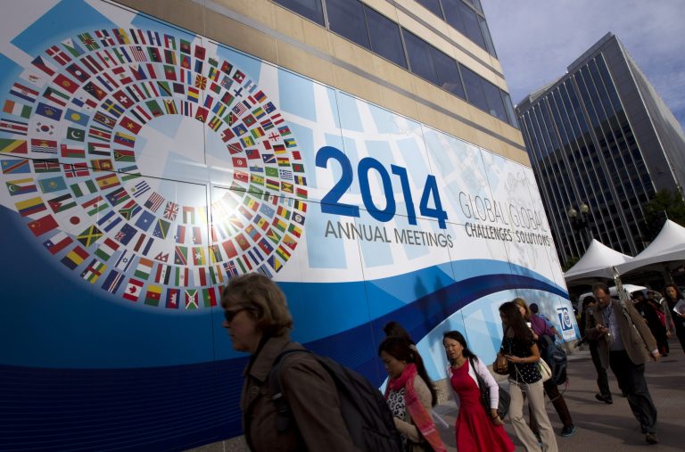 People walk past the International Monetary Fund (IMF) headquarters in Washington, Thursday, Oct. 9, 2014. The IMF, World Bank, finance ministers and central bank presidents of the Group of 20 nations will hold discussions on Oct. 10. Treasury Secretary Jacob Lew and Federal Reserve Chair Janet Yellen will represent the United States.  (AP Photo/Jose Luis Magana)