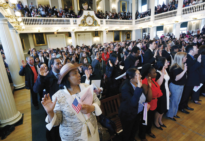 Gina Dominique, lower left, who came from Haiti, takes the oath of U.S. citizenship during a naturalization ceremony. (AP Photo/Michael Dwyer)