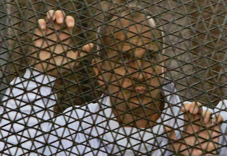 Al Jazeera journalist Peter Greste stands inside the defendants' cage in a courtroom during a trial on terror charges, along with several other defendants, in Cairo Egypt, Wednesday, March 5, 2014. (AP Photo/Mohammed Abu Zaid)