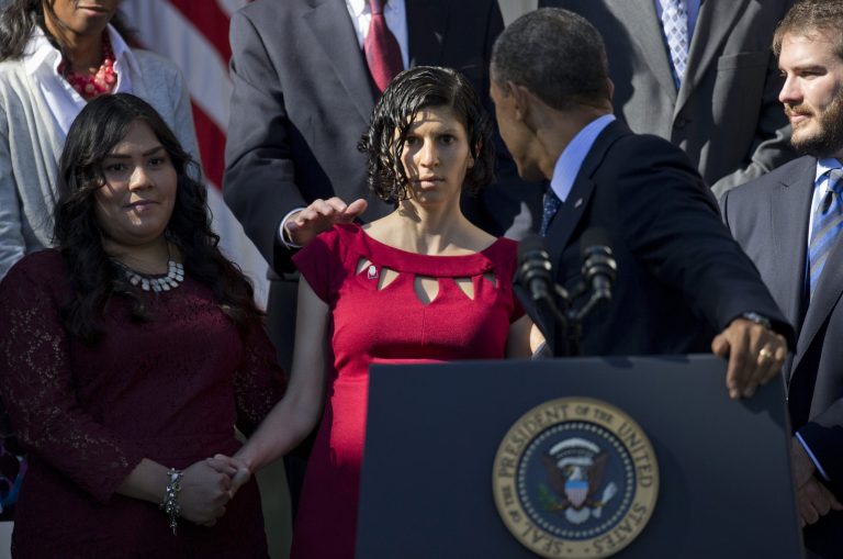President Barack Obama reaches back for a woman who began to lose her balance during an event in the Rose Garden of the White House in Washington, Monday,on the initial rollout of the health care overhaul. (AP/Evan Vucci)