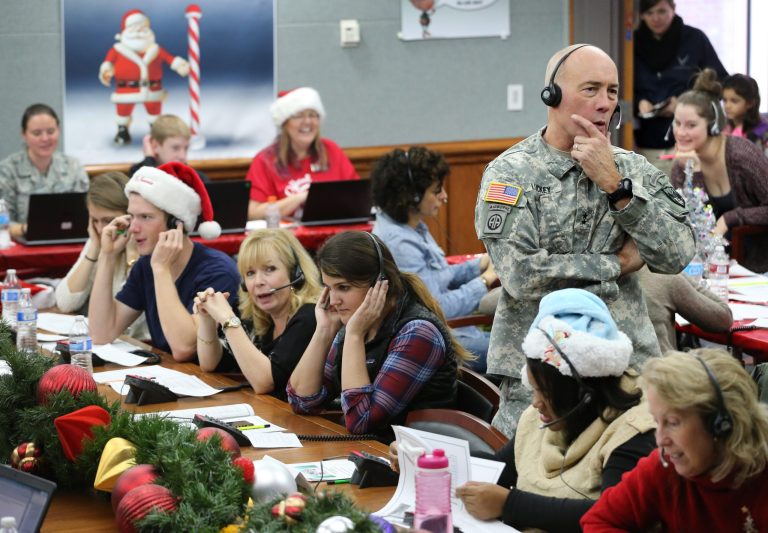 In this Dec. 24, 2014 photo, NORAD and U.S. Northern Command (USNORTHCOM) Chief of Staff Maj. Gen. Charles D. Luckey joins other volunteers taking phone calls from children around the world asking where Santa is and when he will deliver presents to their homes, inside a phone-in center during the annual NORAD Tracks Santa Operation, at the North American Aerospace Defense Command, at Peterson Air Force Base, Colo. Hundreds of military and civilian volunteers at NORAD are estimated to field more than 100,000 calls this year through Christmas Eve, from children from all over the world eager to hear about Santa's progress. (AP Photo/Brennan Linsley)