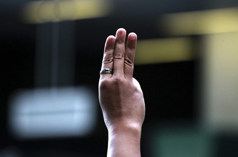 A protester flashes three fingers, representing liberty, brotherhood and equality, during an anti-coup demonstration at a shopping mall in Bangkok, Thailand Sunday, June 1, 2014. Hundreds of demonstrators shouting 