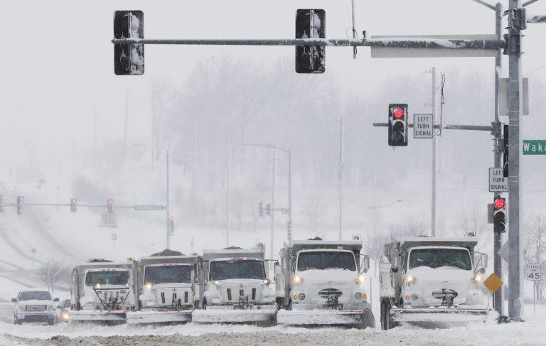 Snow plows stop for a traffic signal as they clear several lanes of West 6th Street in Lawrence, Kan., Sunday, March 24, 2013. Few signs of spring are being found in parts of the Midwest as a snowstorm brings heavy snow and high winds. (AP Photo/Orlin Wagner)
