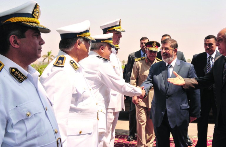 In this photo released by Middle East News Agency, the Egyptian official news agency, President-elect Mohammed Morsi, shakes hands with an Egyptian police general in Cairo, Egypt, Tuesday, June 26, 2012. The military has pledged to turn power over to a civilian government once a new president is named. On Sunday, June 24, 2012, Islamist Mohammed Morsi of the Muslim Brotherhood was declared Egypt's first freely elected president in modern history. (AP Photo/Middle East News Agency, HO)