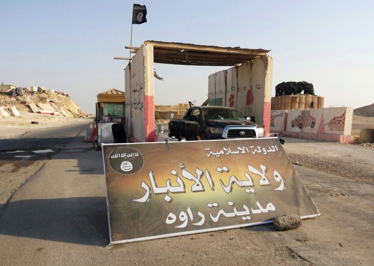In this Tuesday, July 22, 2014 photo, a sign is posted at a checkpoint belonging to the Islamic State group, captured from the Iraqi Army, at the main entrance of Rawah, 175 miles (281 kilometers) northwest of Baghdad, Iraq. Arabic reads,