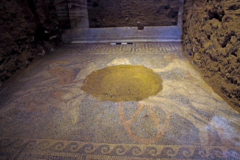 In this picture provided by Greece's Culture ministry on Sunday, Oct. 12, 2014, a partly damaged floor mosaic is shown inside an ancient Greek tomb, depicting a chariot driver, two horses and the Greek god Hermes. Archaeologists digging through an ancient grave at Amphipolis, northern Greece, uncovered the 3-by-4.5 meter (10-by-15 ft.) mosaic in what is likely the antechamber to the main burial room. (AP Photo/Greek Culture Ministry)
