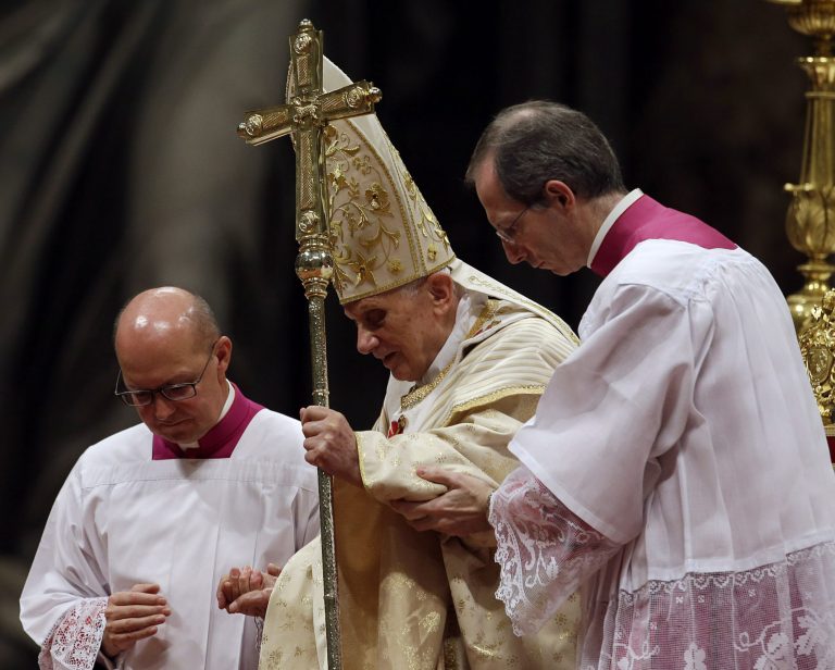   Pope Benedict XVI is helped on to the altar by Bishop Guido Marini, right, during the Christmas Eve Mass in St. Peter's Basilica at the Vatican, Monday, Dec. 24, 2012. (AP Photo/Gregorio Borgia)  