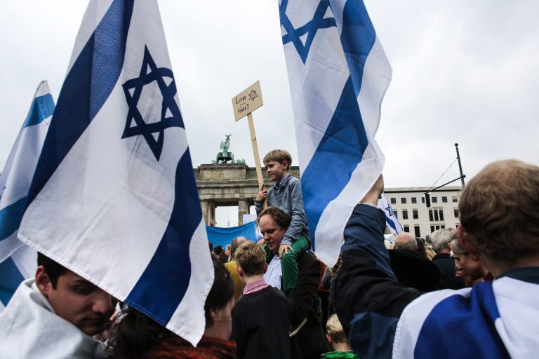 People with Israeli flags and banners attend a rally against anti-semitism near the Brandenburg Gate in Berlin, Sunday, Sept. 14, 2014. Thousands of protesters attend the public rally near the Brandenburg Gate organized by German Jewish Community with the slogan: Stand Up: 'Jew hatred-never again!'. The poster of the boy reads: 'Love not hate'. (AP Photo/Markus Schreiber)