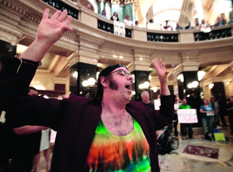 In this Sept. 7, 2012 photo, Brandon Barwick of Madison joins Solidarity Sing Along participants for the 455th consecutive gathering of the protest singers inside the rotunda of the Wisconsin State Capitol building in Madison, Wis. Most of the demonstrations against Wisconsin Gov. Scott Walker ended a long time ago. But every weekday at noon, a few dozen people still gather inside the state Capitol and sing protest songs for an hour. (AP Photo/Wisconsin State Journal, John Hart)
