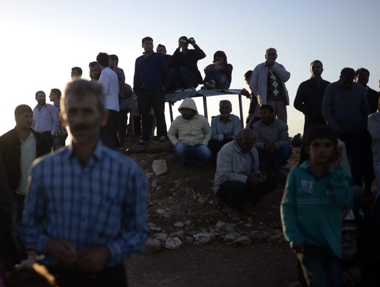 Turkish Kurds watch clashes between Syrian Kurdish fighters and militants of the Islamic State close to Turkey-Syria border near Suruc, Turkey, Sunday, Sept. 28, 2014. (AP Photo)