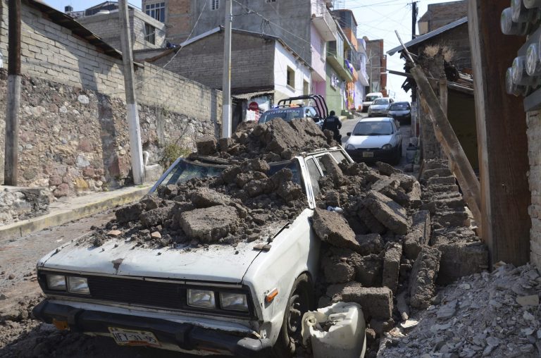 A parked car suffered damage when a adobe wall collapsed on it after a strong earthquake shook Chilpancingo, Mexico, Friday morning, April 18, 2014. A powerful magnitude-7.2 earthquake shook central and southern Mexico but there were no early reports of major damage or casualties. (AP Photo/Alejandrino Gonzalez)