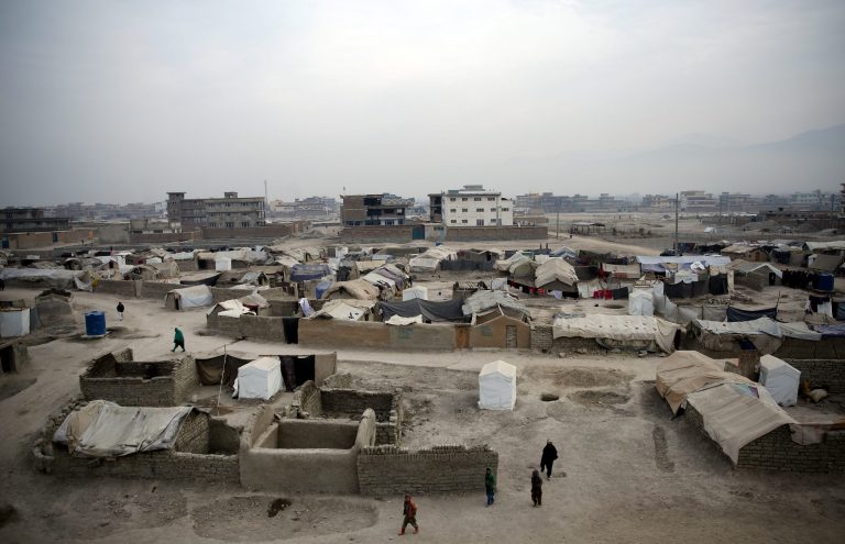 In this Wednesday, Dec. 24, 2014 photo, Afghan internally displaced people walk at a camp in Kabul, Afghanistan. (AP Photo/Massoud Hossaini)