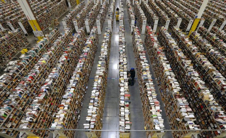 An Amazon.com employee stocks products along one of the many miles of aisles at an Amazon.com Fulfillment Center in Phoenix. The company's market value has tumbled since last week amid a barrage of Twitter attacks from President Trump. 