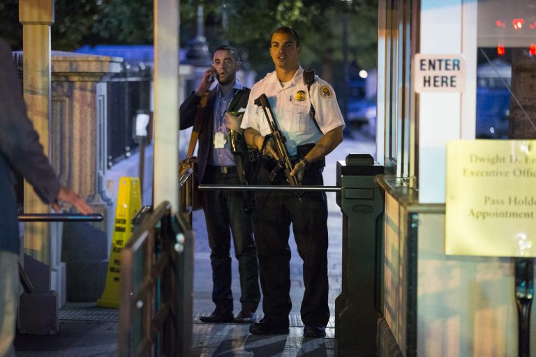 A Secret Service police officer holds a weapon as he stands near an entrance to the White House complex during an evacuation minutes after President Barack Obama departed Washington for Camp David aboard Marine One on Friday, Sept. 19, 2014. A Secret Service agent at the scene says someone jumped the fence surrounding the White House. (AP Photo/Evan Vucci)
