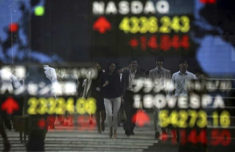 Pedestrians are reflected on an electronic stock board of a securities firm in Tokyo, Tuesday, June 10, 2014. Renewed optimism about the global economy helped push most Asian stock markets higher Tuesday. The Nikkei 225, the benchmark for the Tokyo Stock Exchange, dropped 0.9 percent to 14,994.80, slipping beneath the key 15,000 mark. (AP Photo/Eugene Hoshiko)