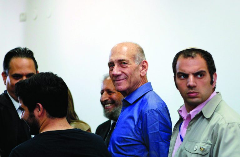 Former Israeli Prime Minister Ehud Olmert stands next to lawyers at Jerusalem's District Court following a verdict hearing in his trial Tuesday, July 10, 2012. An Israeli court on Tuesday cleared Olmert of the major charges in a corruption trial that forced him from power. Olmert was found guilty of a lesser offense, and it was not clear whether that verdict could send him to jail. (AP Photo/Gali Tibbon, Pool)