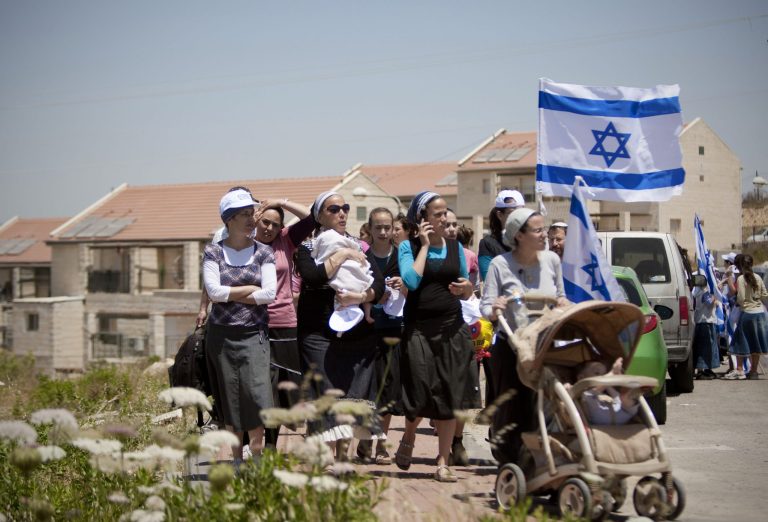   Jewish settlers march during a demonstration against the proposed decision to evacuate a West Bank outpost in the Ulpana neighborhood, in the West Bank settlement of Beit El near the Palestinians city of Ramallah, Monday, June 4, 2012. An Israeli official said on Saturday that Prime Minister Benjamin Netanyahu has decided to remove a West Bank outpost ahead of a court deadline, and is mulling whether to demolish the buildings or relocate them. The signs in Hebrew call on cabinet ministers to support a law preventing the evacuation. (AP Photo/Ariel Schalit)  