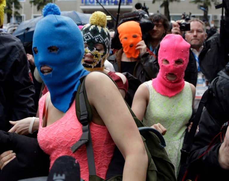 Russian punk group Pussy Riot members Nadezhda Tolokonnikova, in the blue balaclava, and Maria Alekhina, in the pink balaclava, make their way through a crowd after they were released from a police station, Tuesday, Feb. 18, 2014, in Adler, Russia. No charges were filed against Tolokonnikova and Alekhina along with the three others who were detained. (AP Photo/Morry Gash)