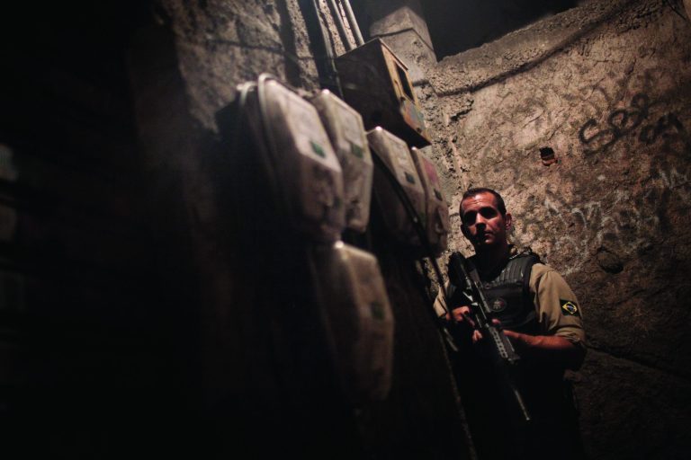 ADVANCE FOR USE MONDAY, JAN. 14, 2013 AND THEREAFTER - FILE - In this Sunday, Nov.,13, 2011 file photo, a police officer patrols an alley at Rocinha slum in Rio de Janeiro, Brazil. Since 2011 police have seized control of dozens of favelas from drug gangs, and things have changed so dramatically that some are now seen as hot real estate investments. Rio's slum 