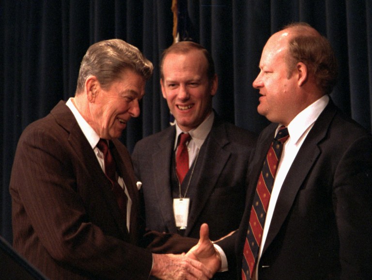 President Ronald Reagan, left, shakes hands with Office of Management and Budget Director James Miller, while Defense Secretary William Howard Taft IV looks on in 1986. The Reagan transition included a team whose sole mission was to identify the critical power paths within each department and major agency. (AP Photo/Dennis Cook)