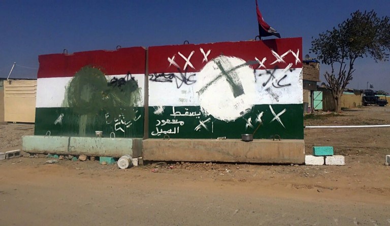 Barriers with defaced Kurdish flags are seen outside of an evacuated checkpoint in the village of Bashir, south of Kirkuk, Iraq, Friday, Oct. 13, 2017. Kurdish forces have withdrawn from the edges of a disputed region in northern Iraq, a commander said Friday, amid tensions with Iraq's central government over the administration of the oil-rich city of Kirkuk. The sentence on the barrier in Arabic reads: 