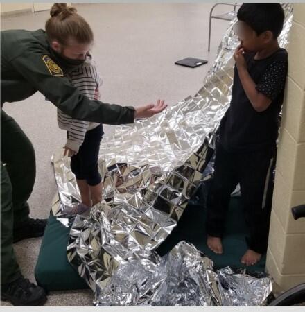 An agent comforts the siblings by the fort they made from disposable mylar blankets.