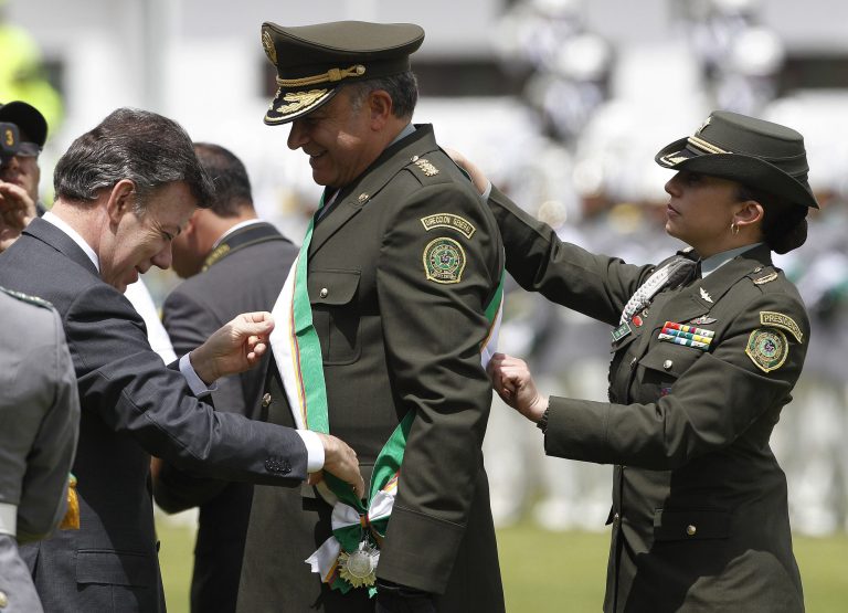   Former National Police Chief Gen. Oscar Naranjo, center, is decorated by President Juan Manuel Santos during the swearing-in ceremony of Naranjo's replacement in Bogota, Colombia, Tuesday, June 12, 2012. Gen. Jose Roberto Leon Riano replaced Naranjo. (AP Photo/Fernando Vergara)  