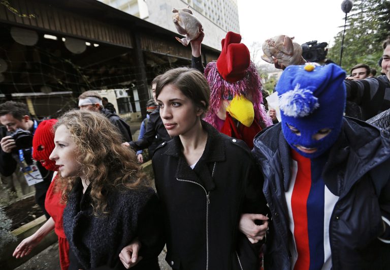 Pussy Riot members Nadezhda Tolokonnikova, center, and Maria Alekhina, left, arrive for a press conference while followed by a person in a chicken costume protesting the punk group - who have feuded with Vladmir Putin's government for years - Thursday, Feb. 20, 2014, in Sochi, Russia. (AP Photo/David Goldman)