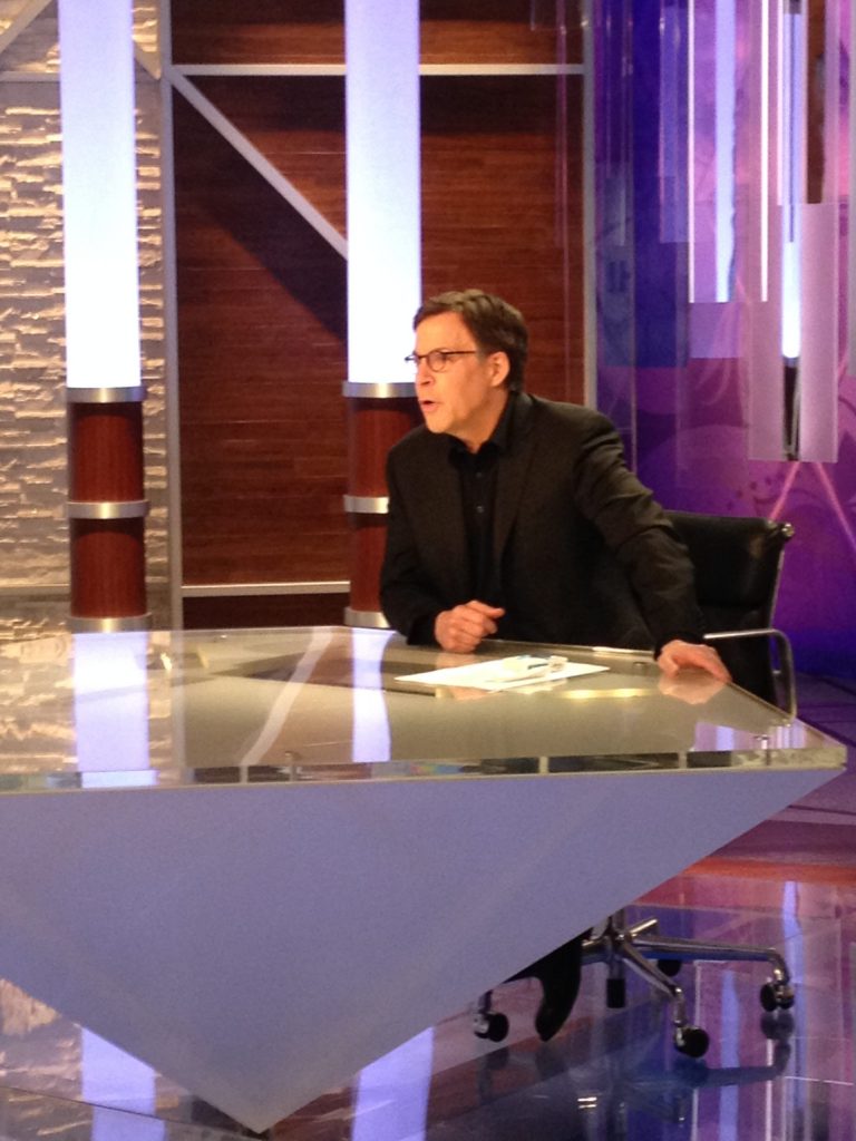 In a photo provided by NBC Olympics, NBC's Bob Costas prepares for broadcast at an anchor desk in Sochi, Russia, Sunday, Feb. 16, 2014. Costas plans to make his return to NBC on Monday after being off the air for a week with an eye infection. (AP Photo/NBC Olympics)