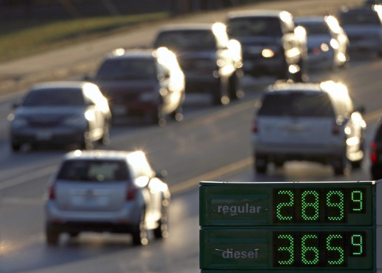 FILE - In this Tuesday, Nov. 26, 2013, file photo, motorists drive past a gas station selling regular unleaded gasoline for less than $3.00 a gallon, in Independence, Mo. Higher gasoline prices are on the way for 2014, but the spring surge may be tamer than in recent years (AP Photo/Charlie Riedel, File)