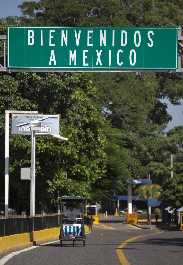 In this Friday, July 11, 2014 photo, a tricycle rides on the bridge that connects Tecun Uman, Guatemala, with Ciudad Hidalgo, Mexico. At the Mexican border town of Ciudad Hidalgo, raft operators ferry constant streams of Guatemalans and other Central Americans across the broad Suchiate River in improvised rafts made of truck inner tubes lashed to wooden boards, in plain view of Mexican police on the shore and immigration agents posted on a bridge over the river that links the two countries.  (AP Photo/Eduardo Verdugo)