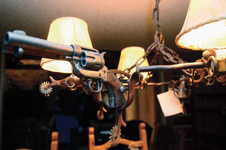   A chandelier made of revolvers, spurs and cowhide shades is seen Friday, Dec. 7, 2012, inside one of the homes owned by former Dixon, Ill., comptroller Rita Crundwell during a tour provided by the U.S. Marshals Service for prospective property buyers and the media. Crundwell pleaded guilty last month to embezzling $53 milliion from the small city in Illinois to fund a lavish lifestyle that included a nationally known horse-breeding operation. The spoils of Crundwell's looting are on the auction block, being sold for pennies on the dollar by the U.S. Marshals Service. (AP Photo/Sauk Valley Media, Alex T. Paschal)  