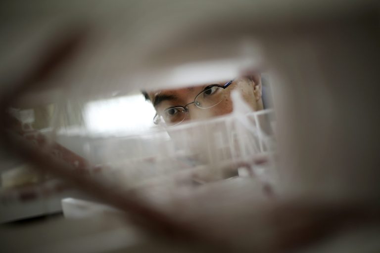 In this June 18, 2014 photo, Japanese architect Sou Fujimoto looks at a scale model of a building he designed at his office in Tokyo. A new generation of Japanese architects believes the world has fallen out of love with the 20th century steel and concrete skyscraper. They are pushing a human-friendly alternative that some say have roots in the elegant simplicity of the traditional Japanese tea house. Instead of pursuing monuments that cry out with a message of economic or corporate power, these Pritzker Prize-winning architects are scoring success with a uniquely Japanese reinterpretation of the past. Fujimoto, like other rising Japanese architects, is busy working all over the world, including Germany, the U.S., France and China. Eighty percent of his work is from outside Japan, and half of his staff is non-Japanese. (AP Photo/Eugene Hoshiko)