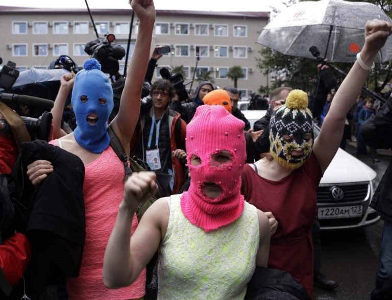 Russian punk group Pussy Riot members Nadezhda Tolokonnikova, in the blue balaclava, and Maria Alekhina, in the pink balaclava, make their way through a crowd after they were released from a police station, Tuesday, Feb. 18, 2014, in Adler, Russia. No charges were filed against Tolokonnikova and Alekhina along with the three others who were detained. (AP Photo/Morry Gash)