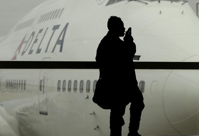 FILE - In this Oct. 29, 2012, file photo, a traveler on Delta Airlines waits for her flight in Detroit.  As federal regulators consider removing a decades-old prohibition on making phone calls on planes, a majority of air travelers oppose such a change, a new Associated Press poll finds on Wednesday, Dec. 11, 2013.  (AP Photo/Charlie Riedel, File)
